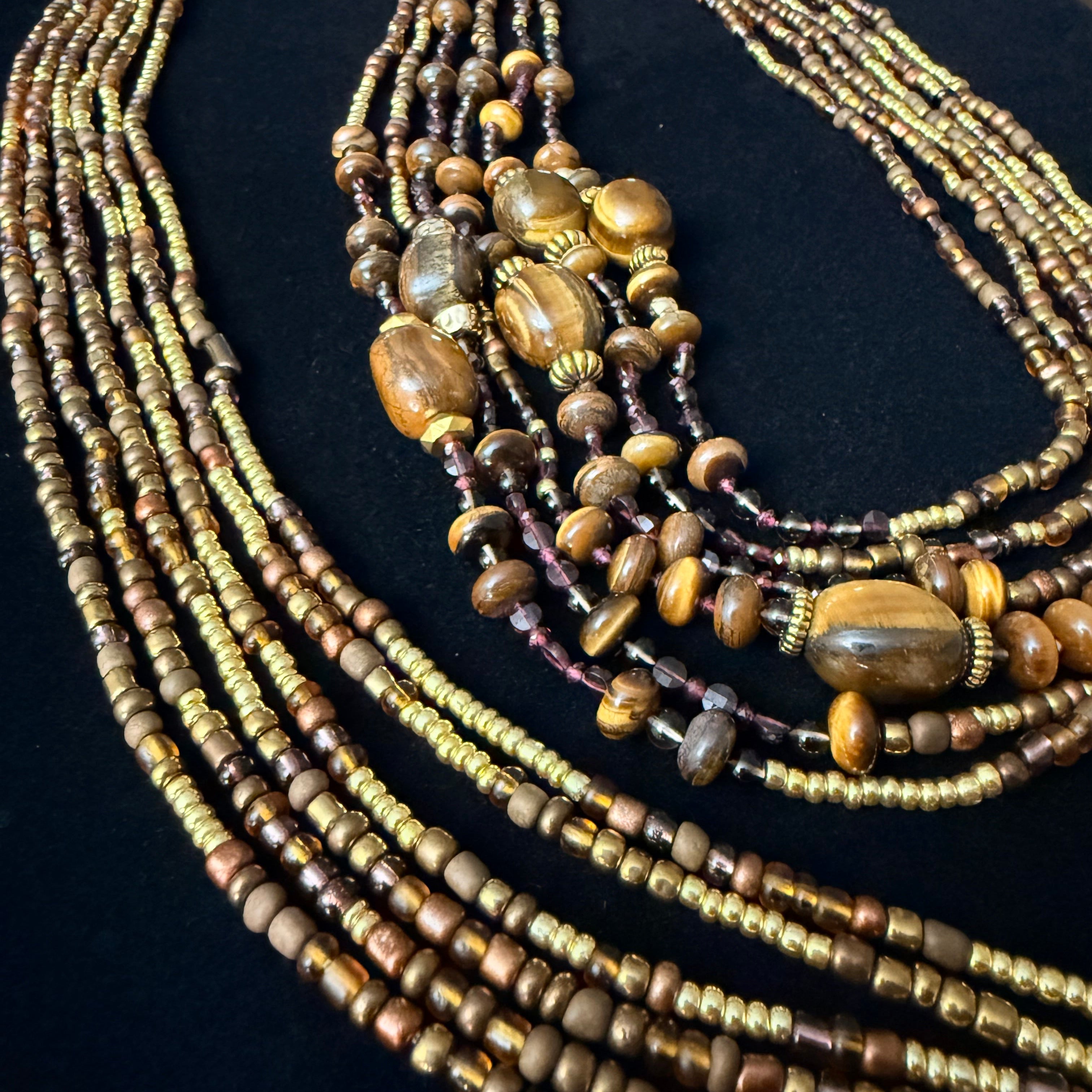 Multiple beaded necklaces on a black stand