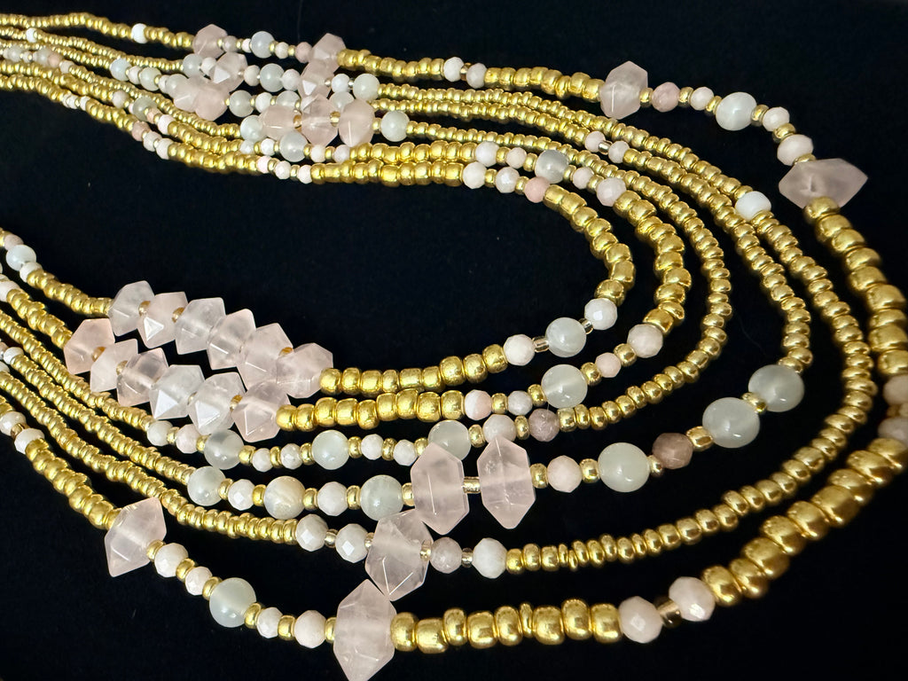 Multiple beaded necklaces with gold and white beads on a black background