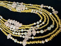 Multiple beaded necklaces with gold and white beads on a black background