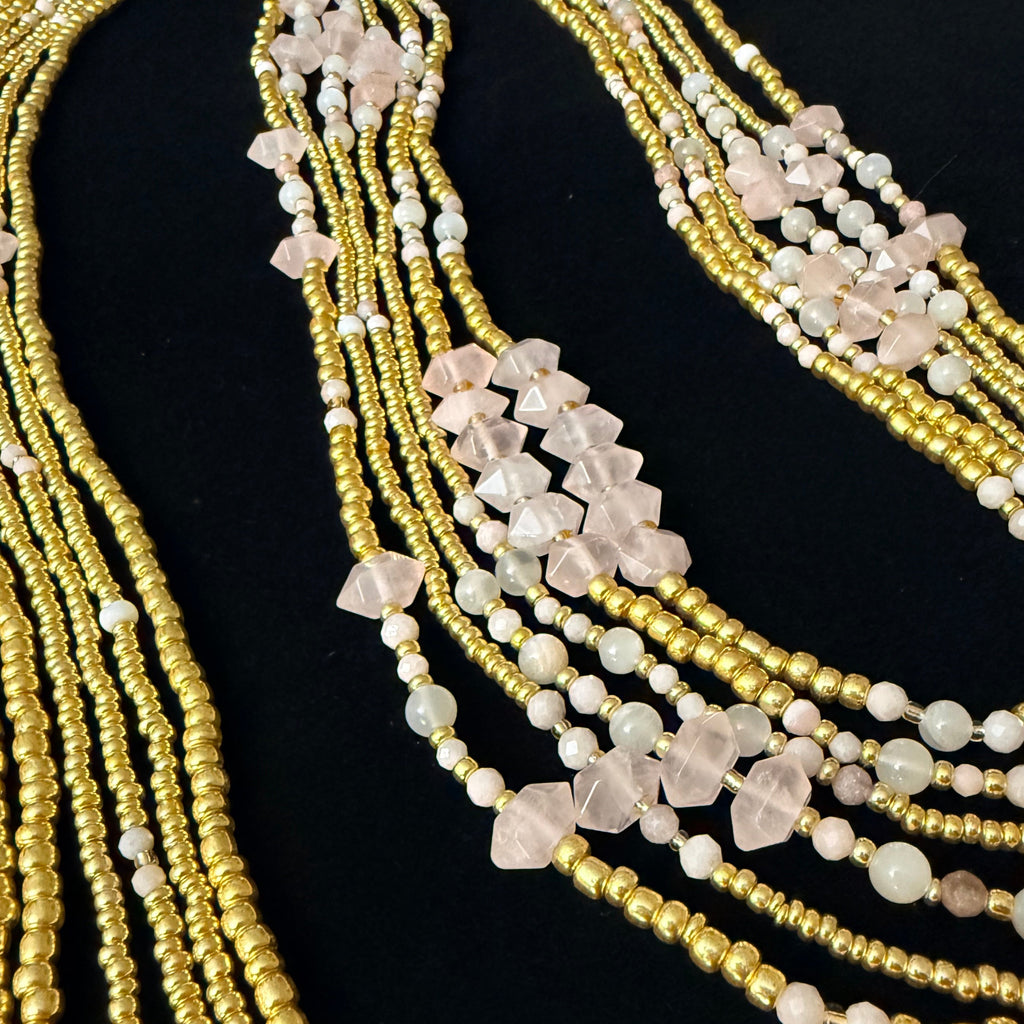 Multiple beaded necklaces with gold and white beads on a black background