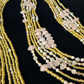 Multiple beaded necklaces with gold and white beads on a black background