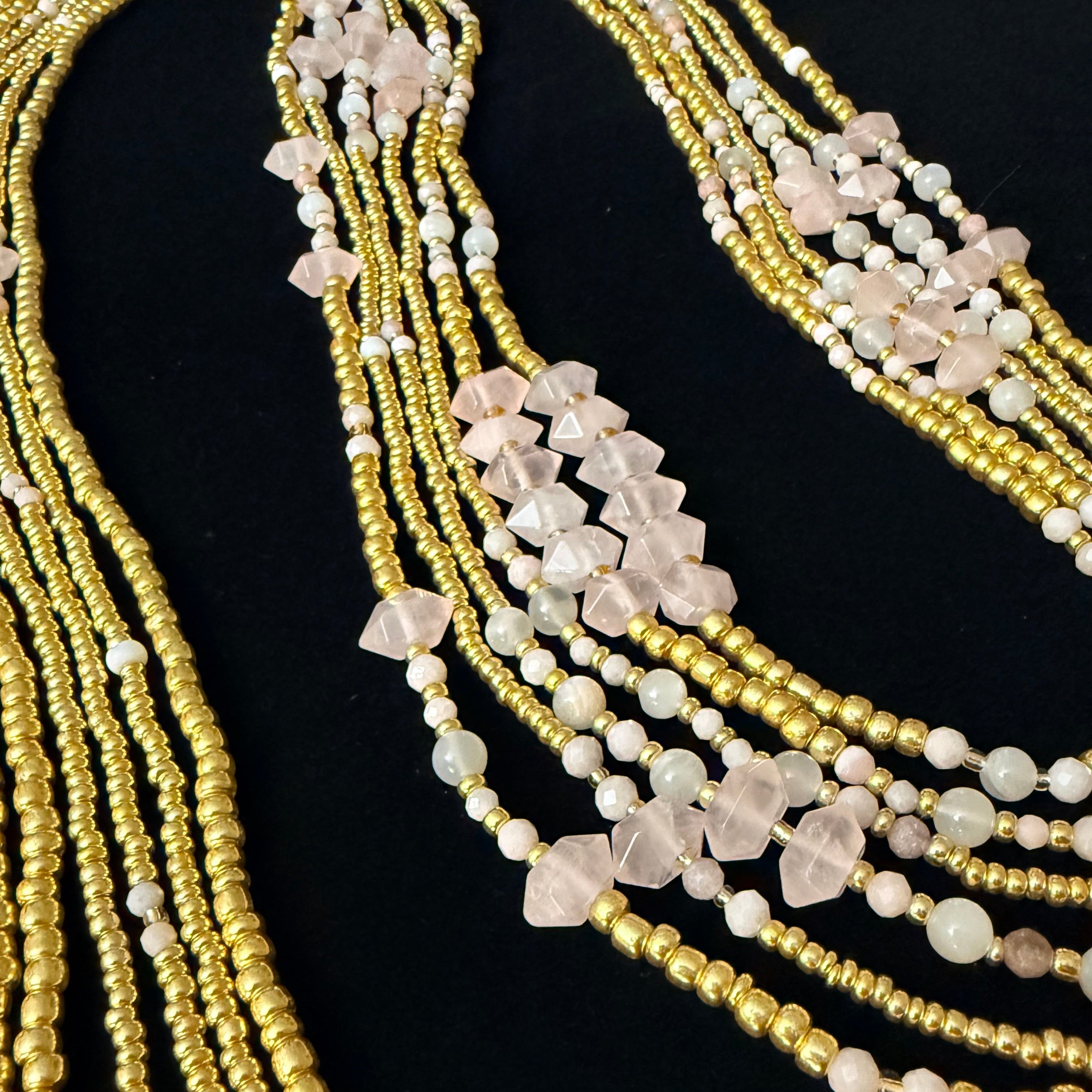 Multiple beaded necklaces with gold and white beads on a black background