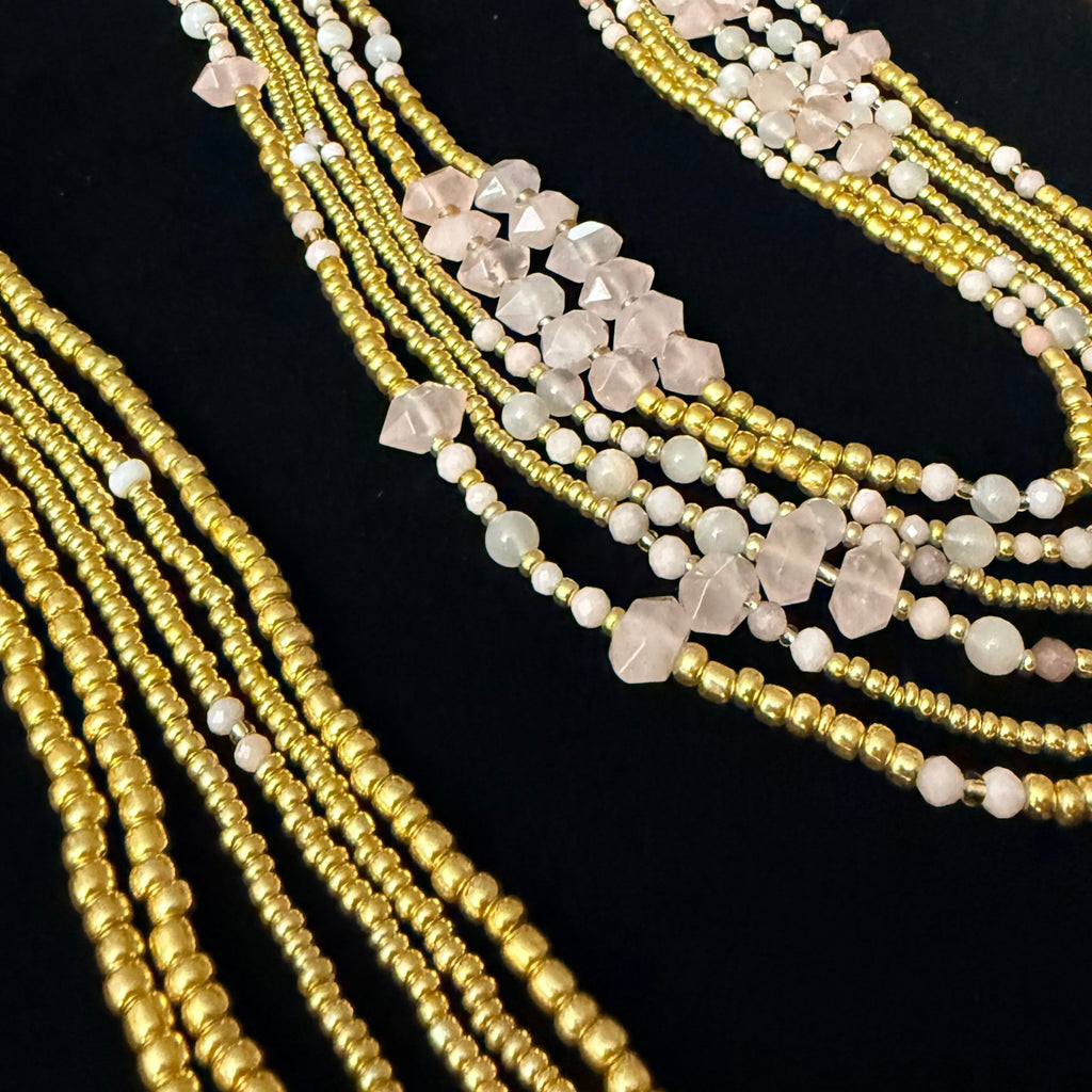 Multiple gold necklaces with gemstones on a black stand