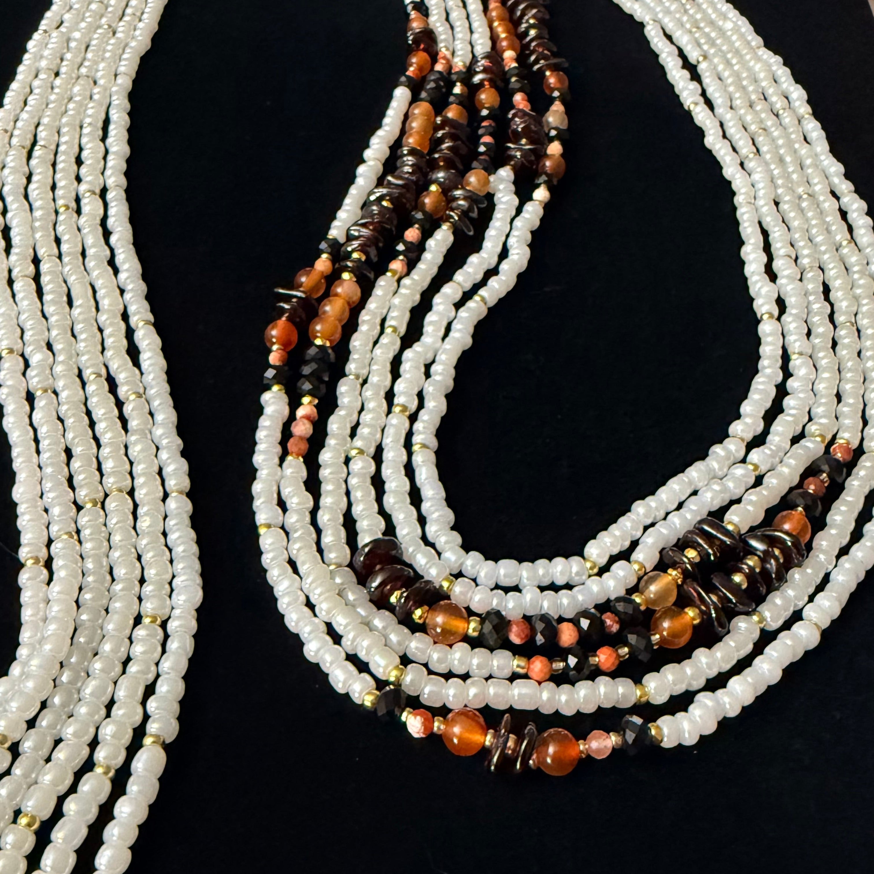 Beaded necklace with white and orange beads on a black background