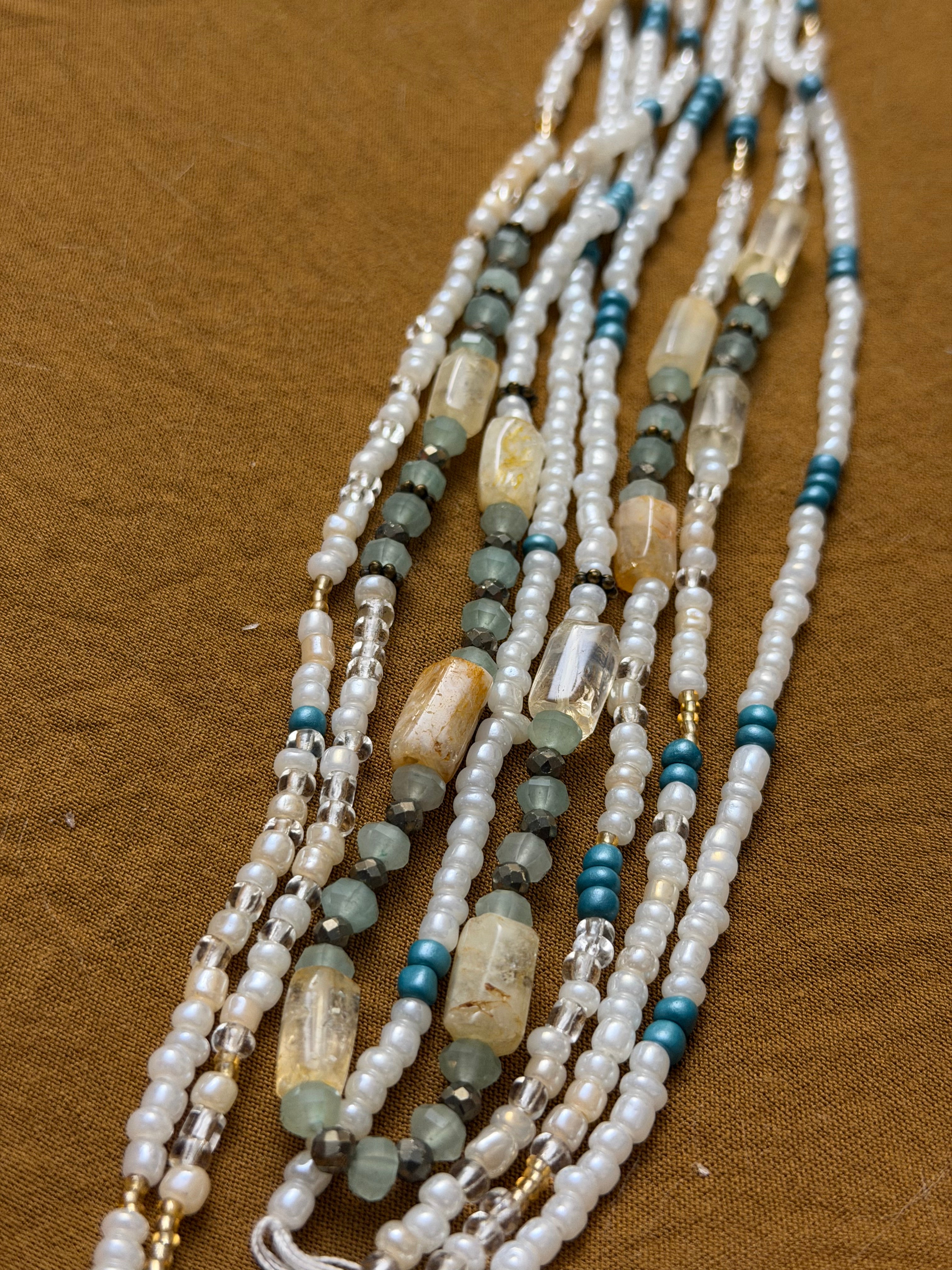 Multistrand beaded necklace with pearls and blue beads on a brown background