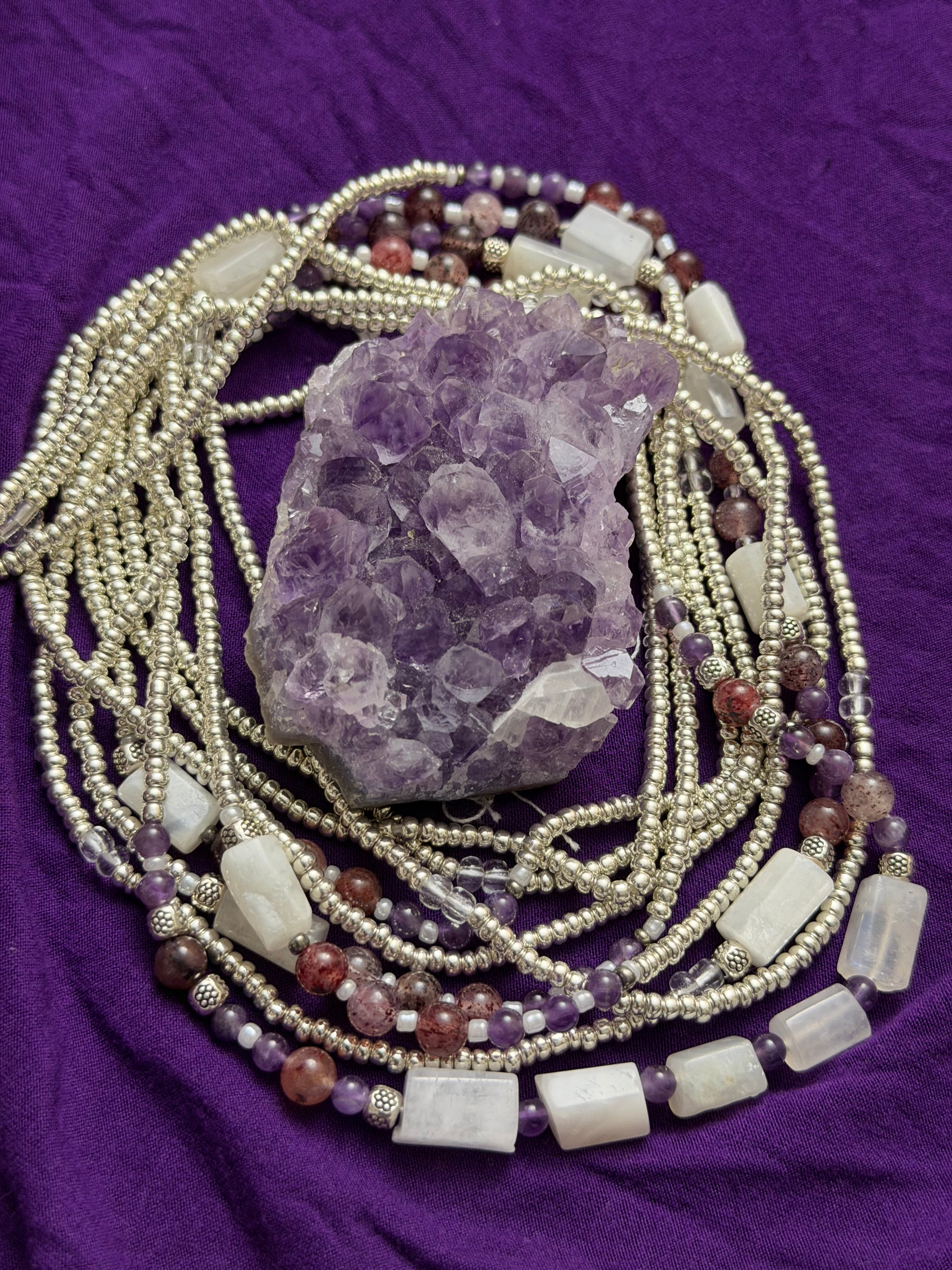 Beaded necklaces with a crystal on a purple fabric background