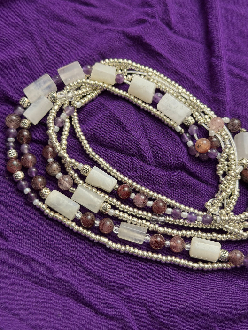 Multistrand beaded necklace on a purple fabric background